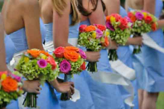 bridesmaids in light blue dresses with bright orange and pink bouquets
