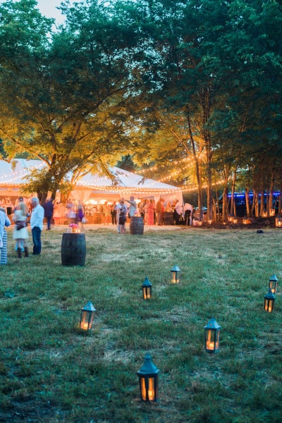 outdoor reception tent with multiple lanterns set up in the grass