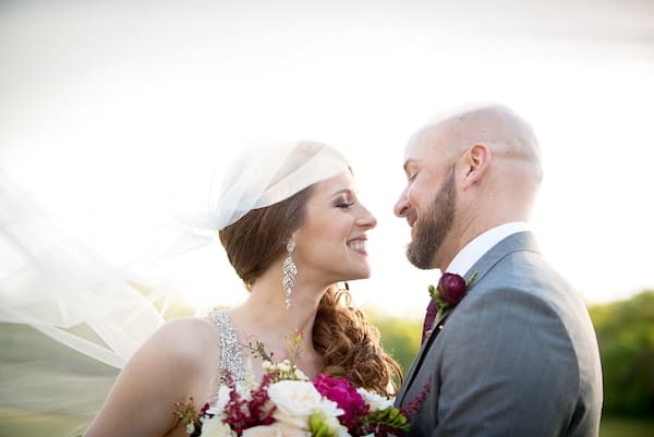 Farm Wedding Bride and groom smiling at each other with veil floating in the wind