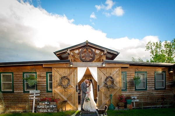 Bride and groom kissing in barn with barn doors open