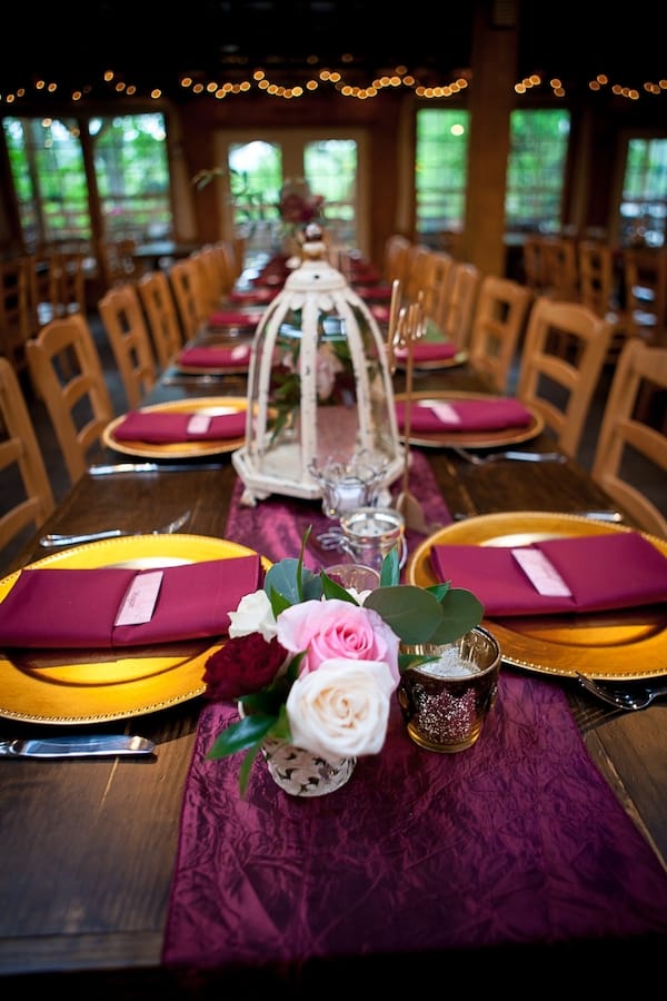 long table with burgundy runner and gold plates