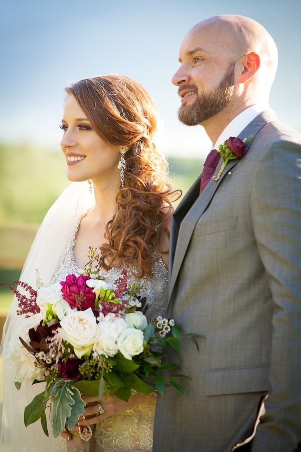 bride and groom standing together with a bouquet of flowers