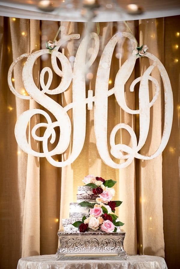 Farm Wedding Wedding cake with floral elements and large initials in the background