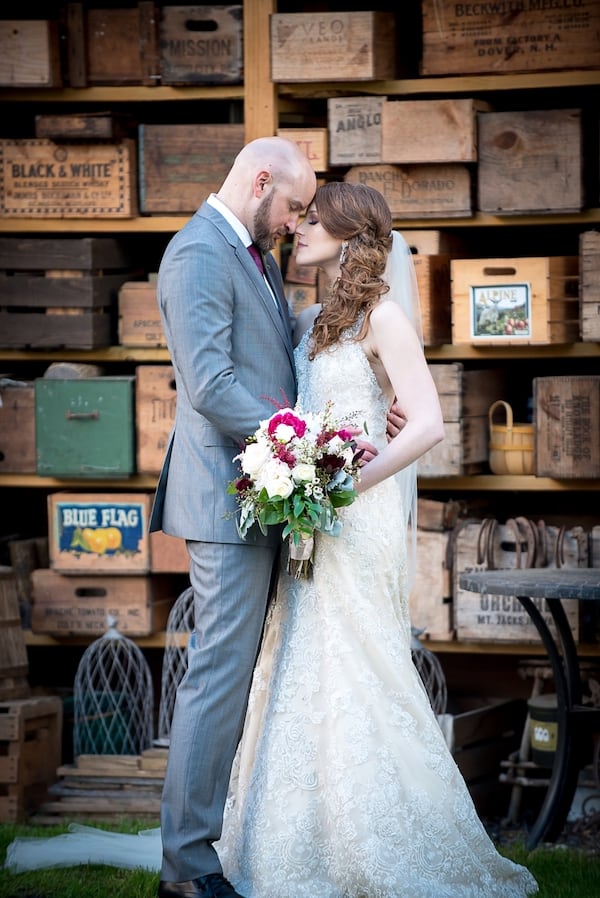 Farm Wedding Bride and groom with heads pressed together in front of wall of crates
