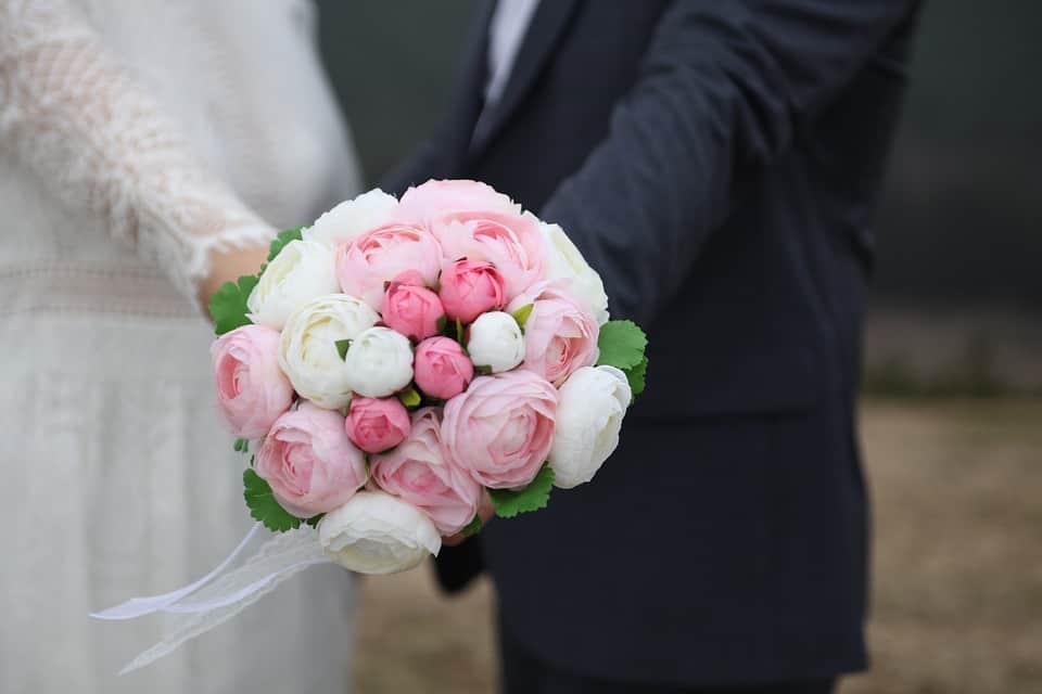 bride and groom holding pink and white bridal bouquet