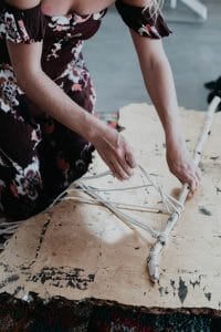 woman in dress wrapping string around branch