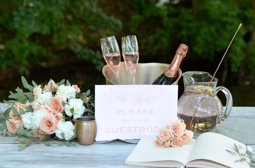 pink champagne in a bucket with guestbook and flowers