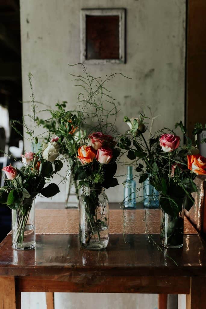 pink and orange rose centerpieces in vases of differing heights