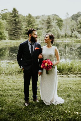 bride and groom looking at each other in front of a pond
