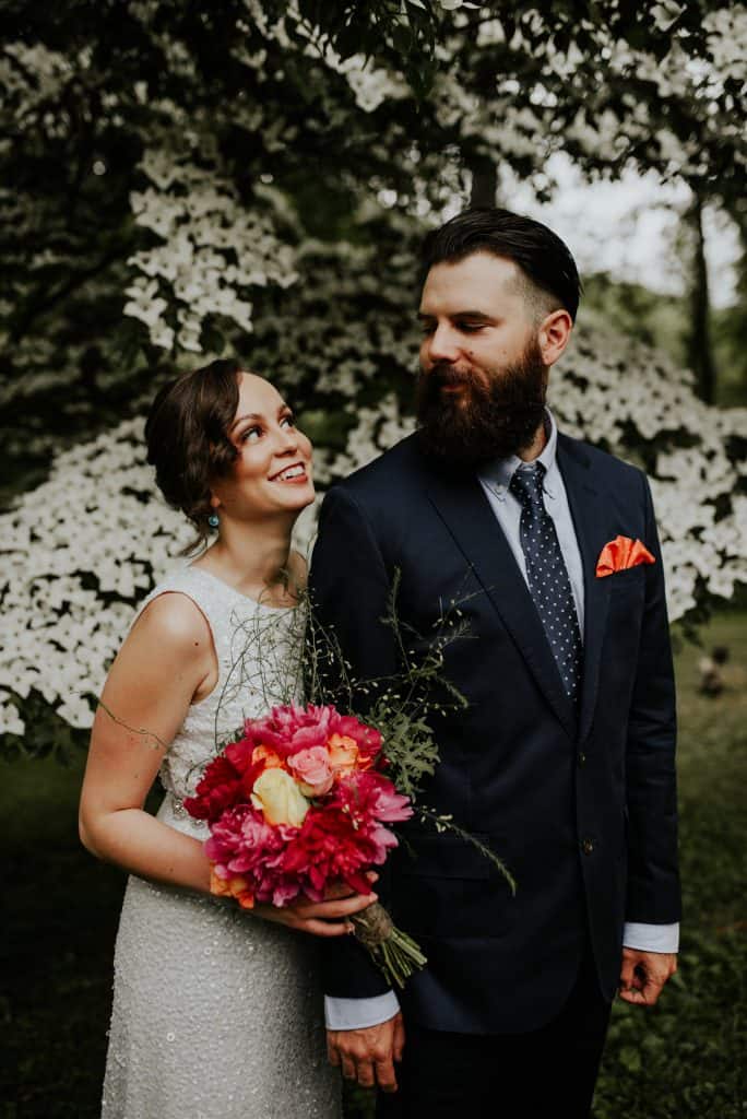 bride and groom with bride holding red bridal bouquet