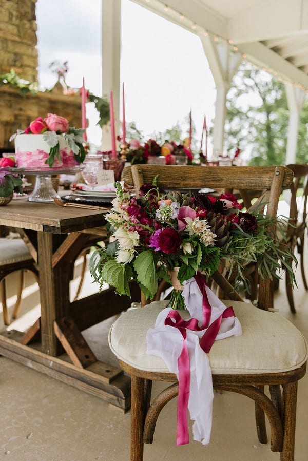 red and white floral bouquet on a chair with table and white and red cake in the background