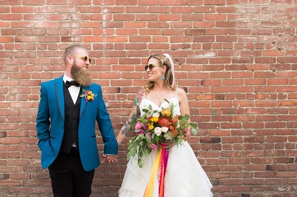 Bride and groom standing in front of a brick wall