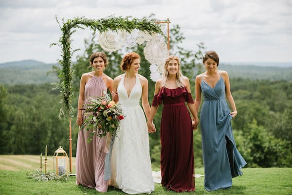 bride and three bridesmaids walking in a field