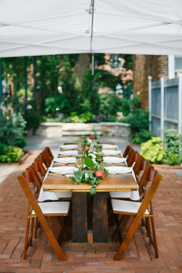 wooden table with garland runner containing white flowers and peaches with brick background