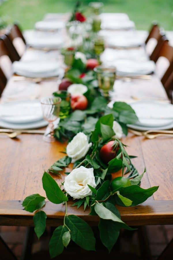 close up of wooden table with garland runner containing white flowers and peaches