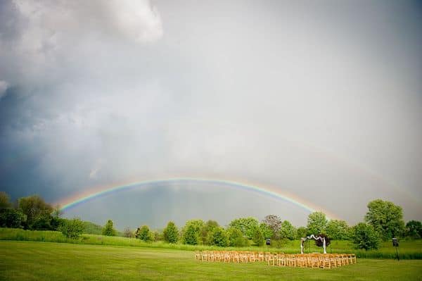 a rainbow over chairs for an outdoor wedding