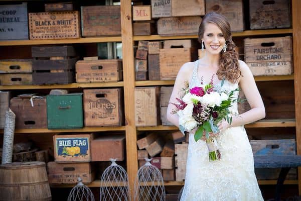bride holding a pink and white floral bouquet in from of stacked wooden boxes