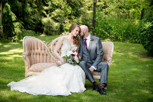 bride and groom sitting next to each other on an outdoor couch