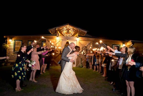 bride and groom kissing outdoors with guests holding sparklers