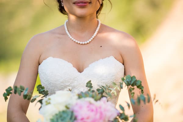 bride wearing pearls holding a pink and white bridal bouquet