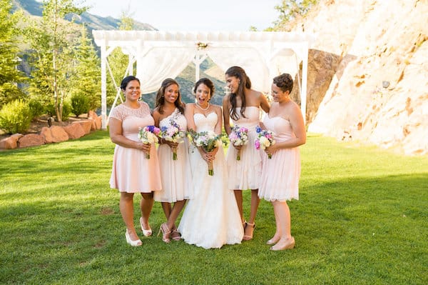 bridal party and bride outdoors on grass standing with bouquets