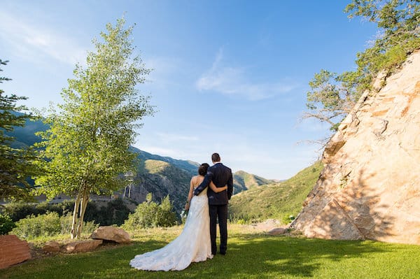 bride and groom looking into the distance with blue sky and mountain background