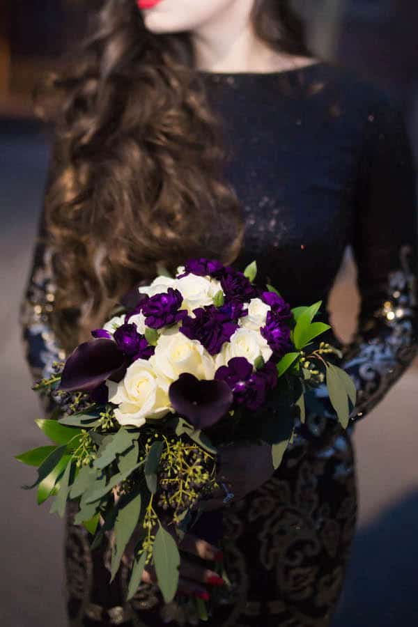 woman in black dress holding purple and white flower bouquet