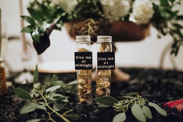 two glass vials with signs saying kiss me at midnight