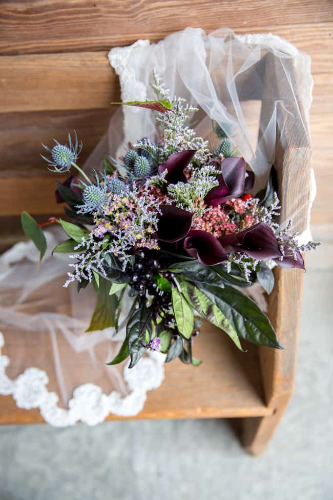purple and green bridal bouquet wrapped in lace on wood