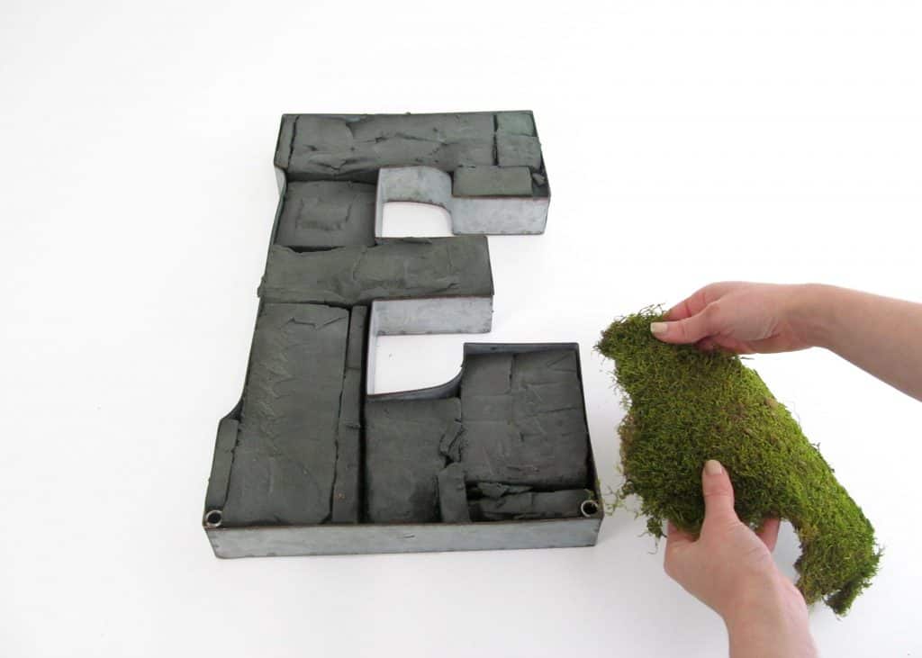 sheet metal form of letter E filled with floral foam and adding the first piece of moss