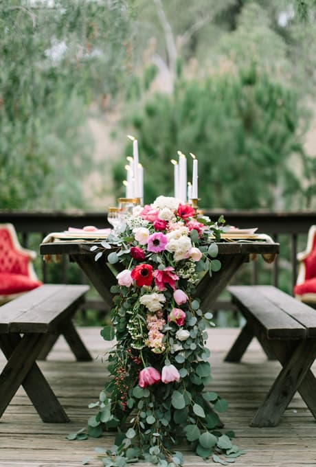 long garland with red and white flowers hanging of the end of a wooden table