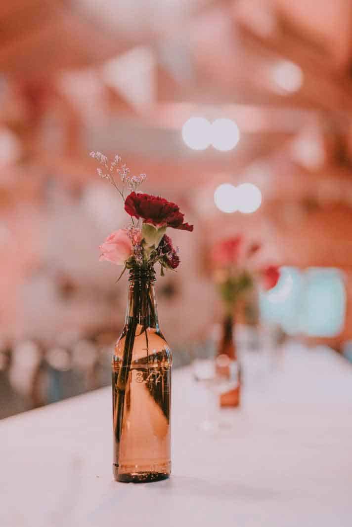 red and pink flowers in a glass bottle with baby's breath