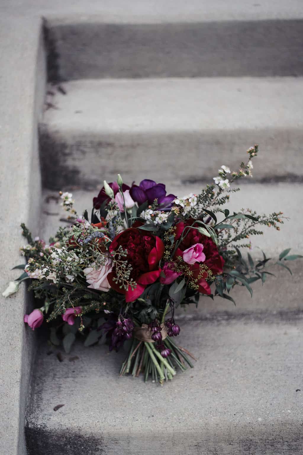 purple and red bouquet leaned up against steps