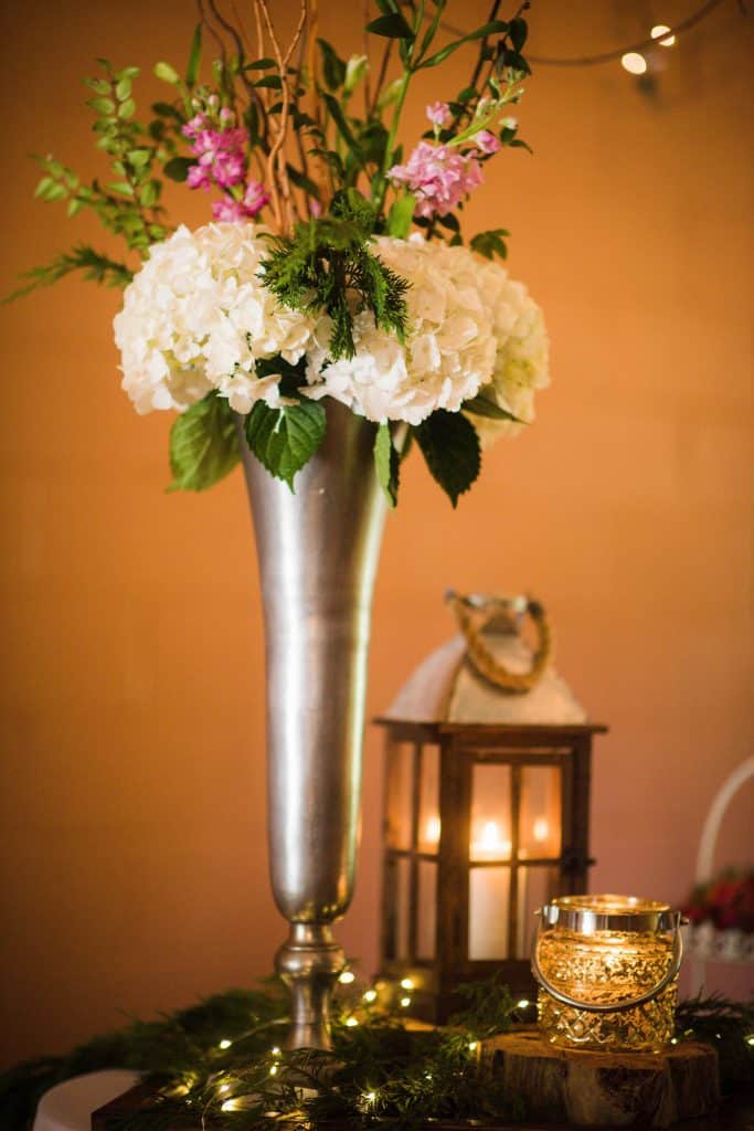 white and pink flower arrangement in a tall silver vase