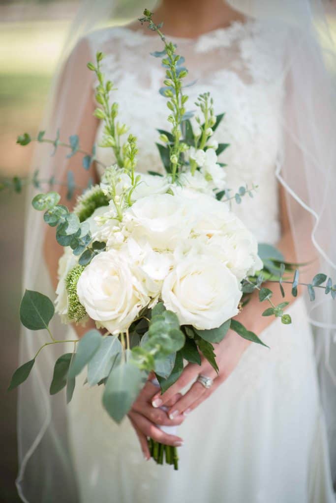 bride in long veil holding white bridal bouquet