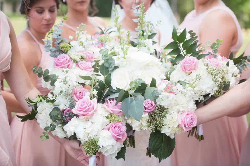 bride and bridesmaids combining bouquets into one large arrangement