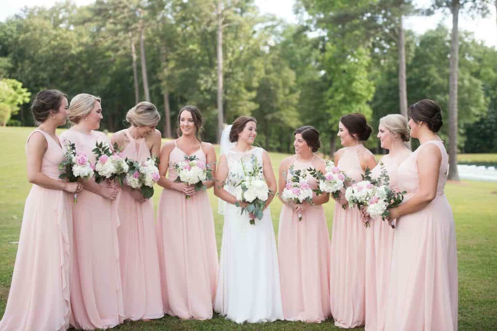 Bride and bridal party in light pink dresses  holding white and blush bridal bouquets
