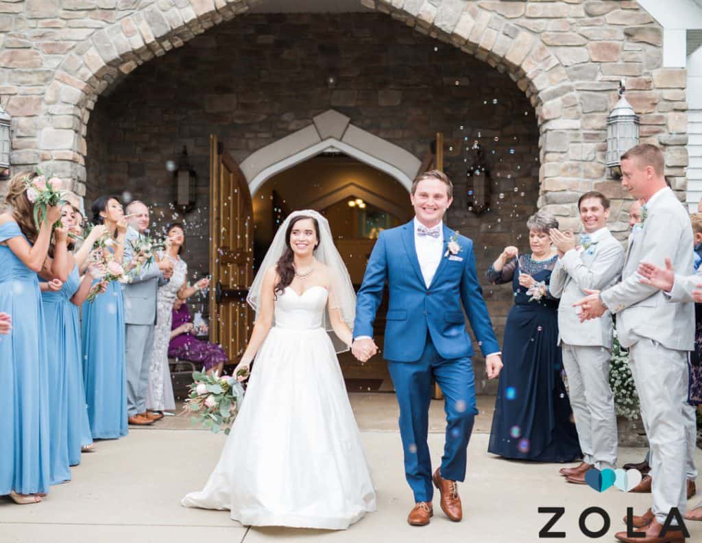 bride and groom holding hands walking out of ceremony surrounded by guests celebrating