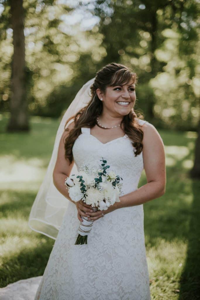 smiling bride holding white flower bouquet
