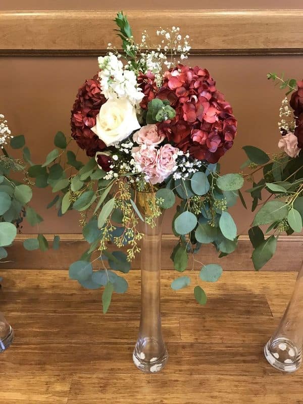 trumpet wedding centerpiece with red and white flowers on tall pedestal