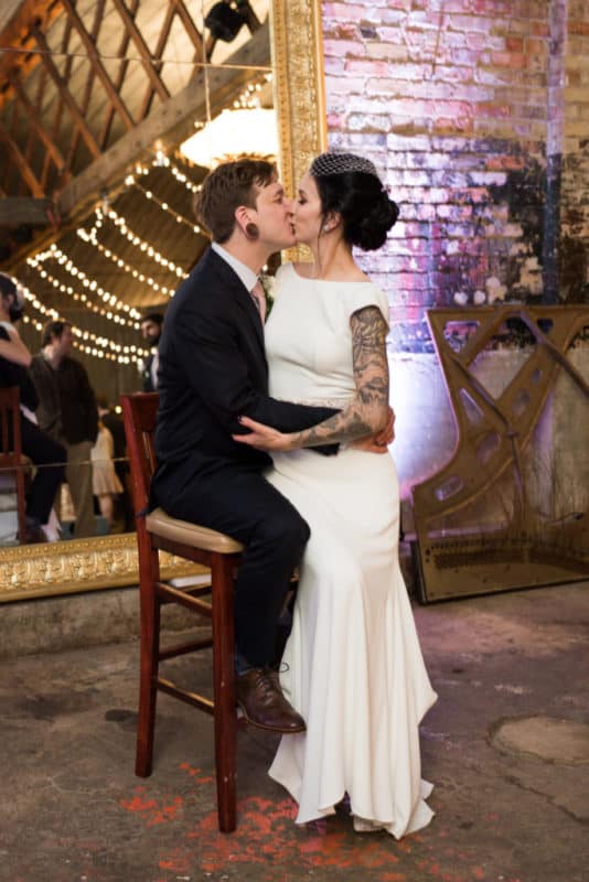 bride and groom kissing on a chair