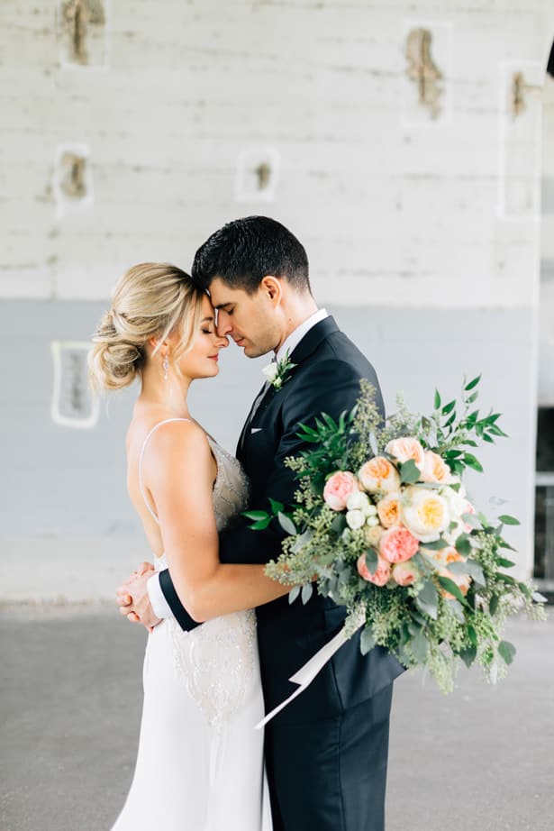 Bride and Groom embracing with pink and white bouquet of flowers