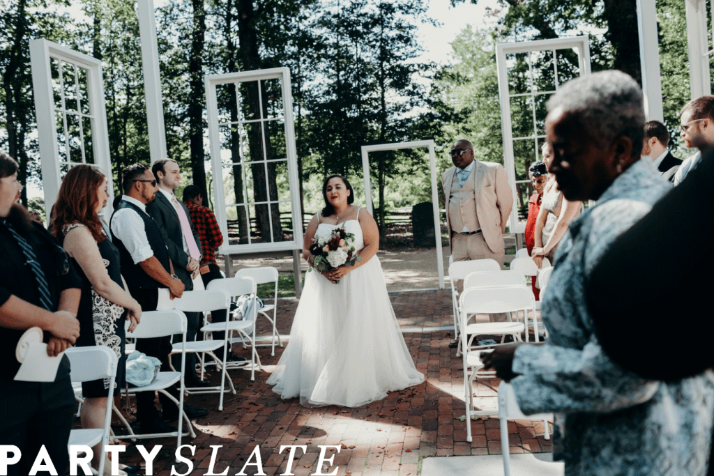 Bride walking down outdoor aisle holding bouquet