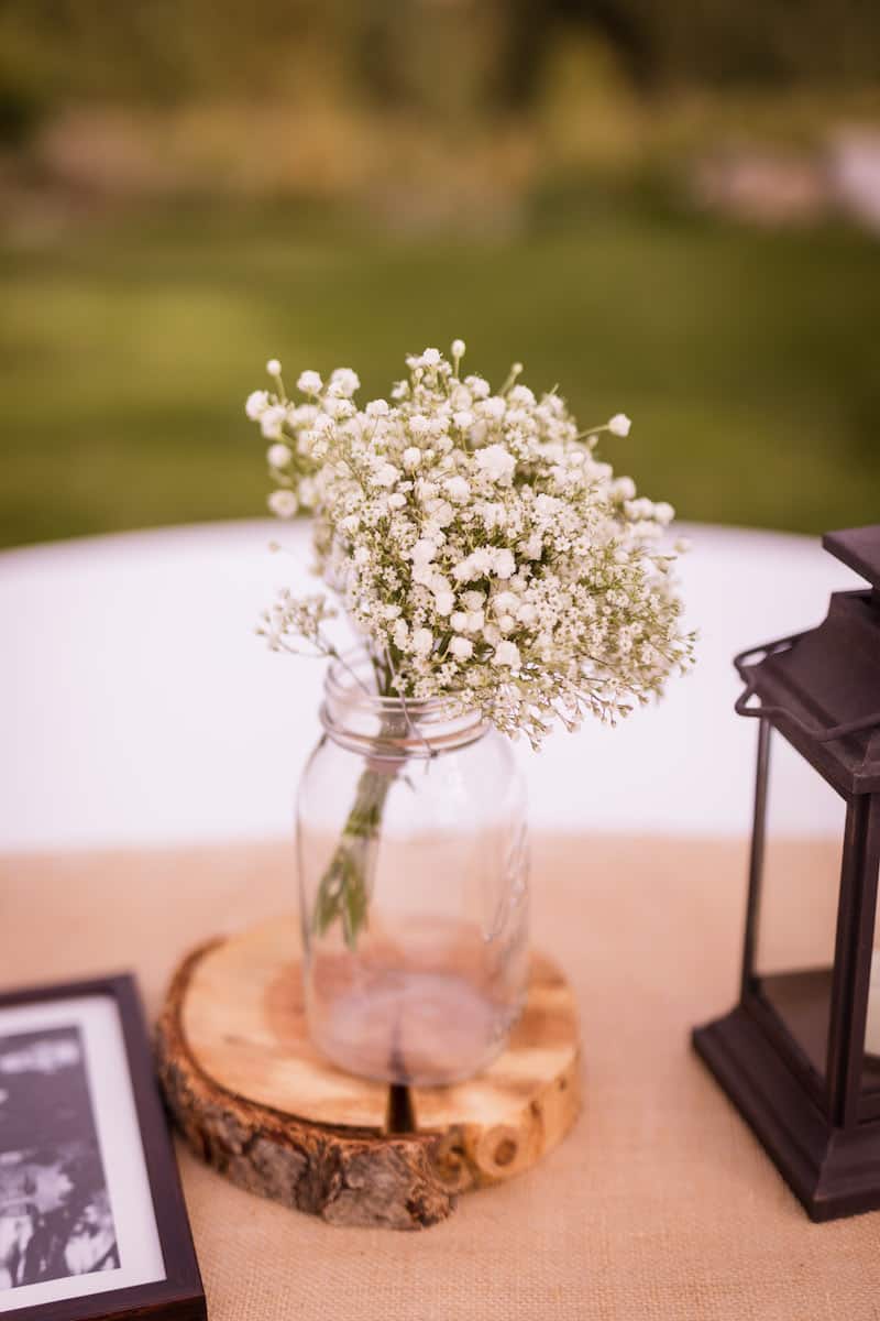 baby's breath in a glass jar on a circular piece of wood