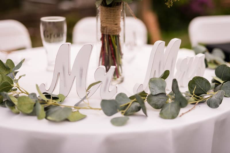 Mr and Mrs cutouts on a table draped with greenery
