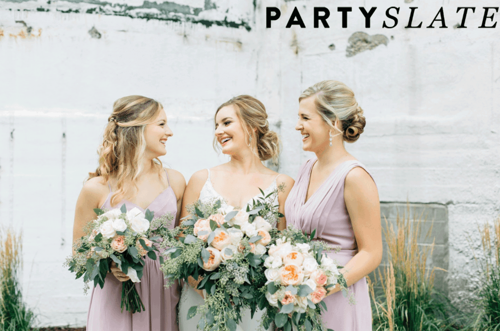 Bride and bridesmaids laughing and smiling holding large bouquets of flowers