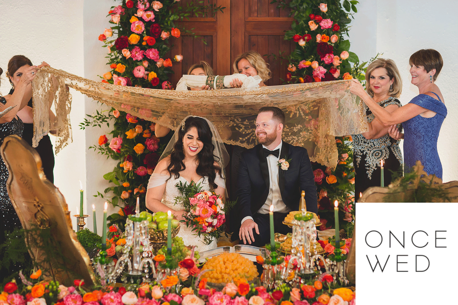 Wedding couple under fabric held up by guests
