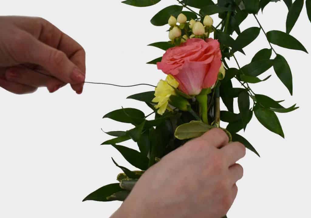 diy floral chair garland tying a pink flower to the greenery