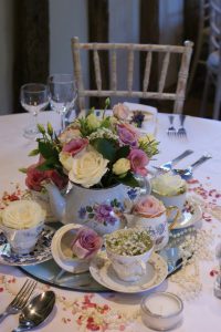 pink and white flowers in a tea kettle as a centerpiece