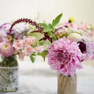 pink flowers in mason jars wrapped with burlap